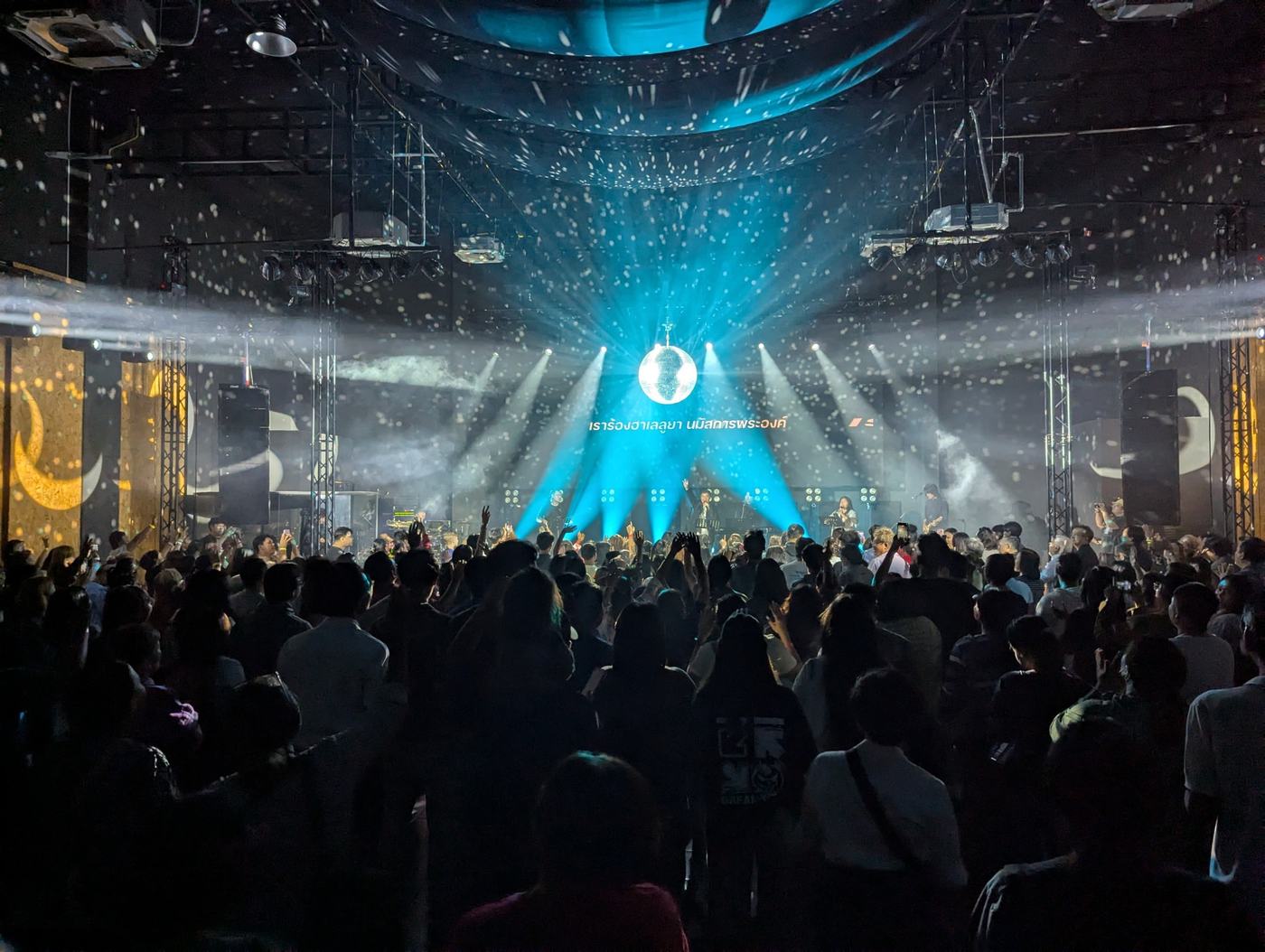 Concert stage lit with cyan beams above a packed crowd